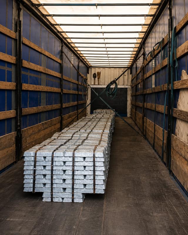 Primary aluminium ingots strapped in stacks inside a curtain-sided trailer.