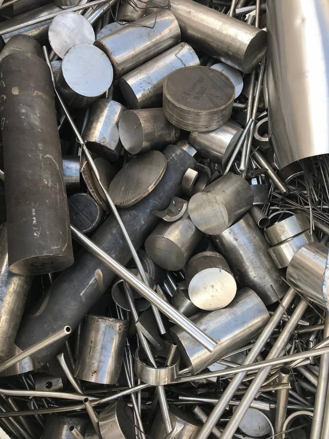 Mixed stainless steel round bar and tube offcuts in a scrap pile.