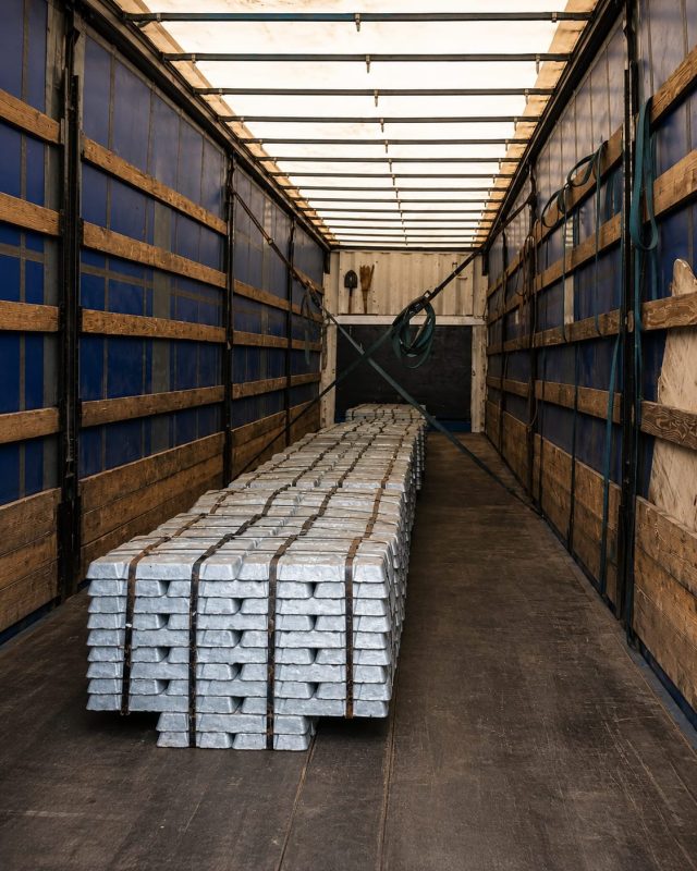 Primary aluminium ingots strapped in stacks inside a curtain-sided trailer.