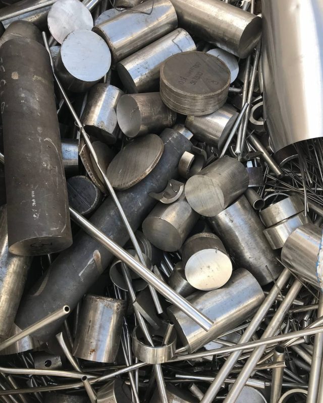 Mixed stainless steel round bar and tube offcuts in a scrap pile.