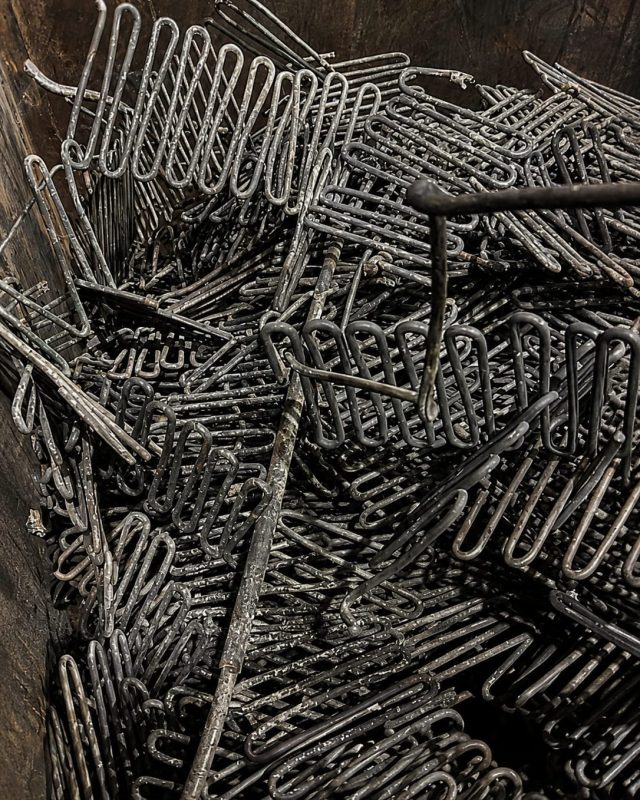 Bent wire and rod offcuts piled in a wooden storage bin.