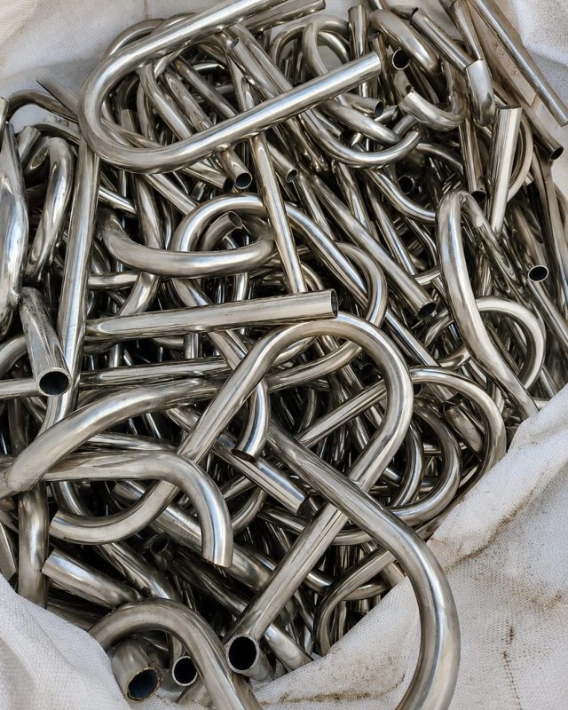 Coiled stainless steel tube scrap gathered in a bulk bag.